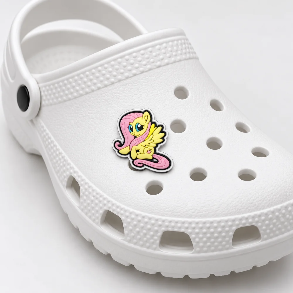 Jibbitz Fluttershy jaune et rose clipsé sur une Crocs blanche